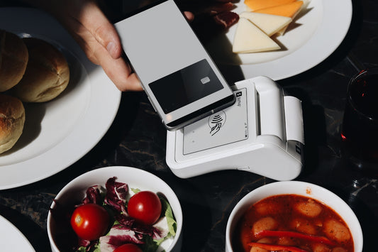 A person holding a cell phone over a table full of food