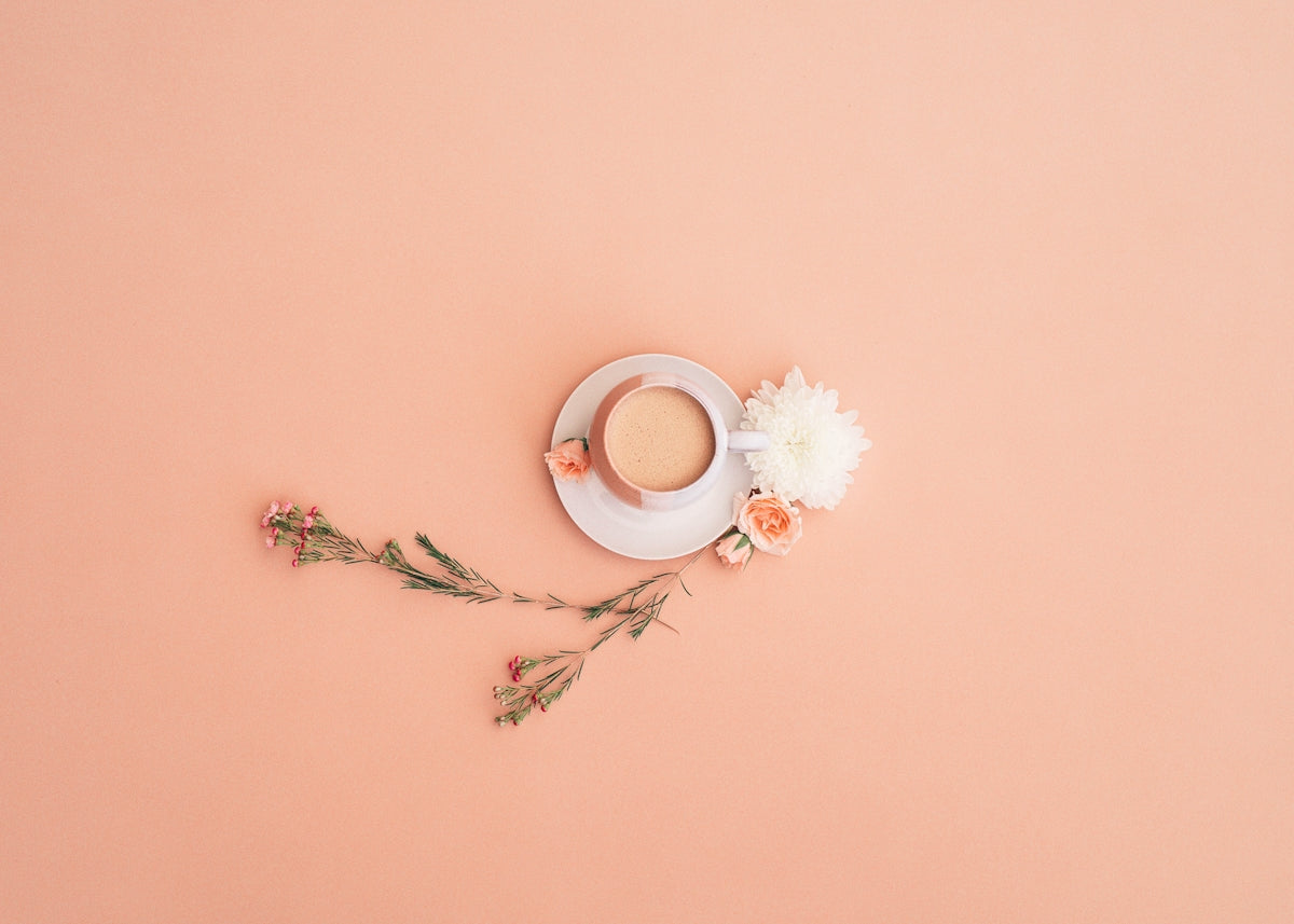 a cup of coffee on a saucer next to flowers