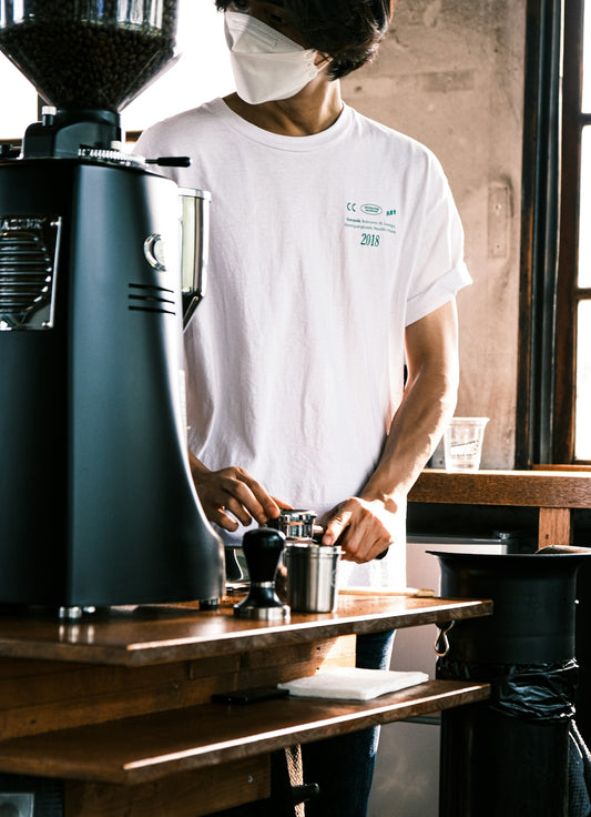 a man wearing a face mask while preparing a drink