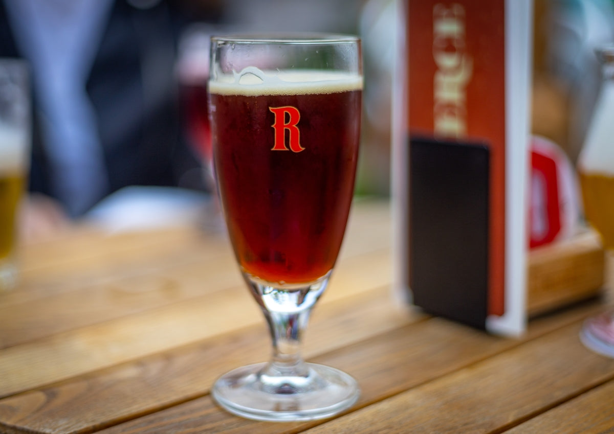 a glass of beer sitting on top of a wooden table