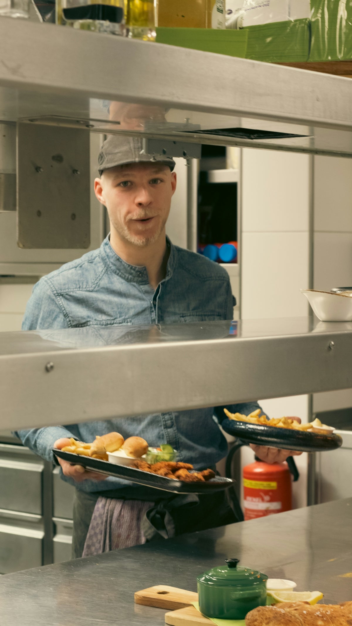 a man holding two plates of food in a kitchen