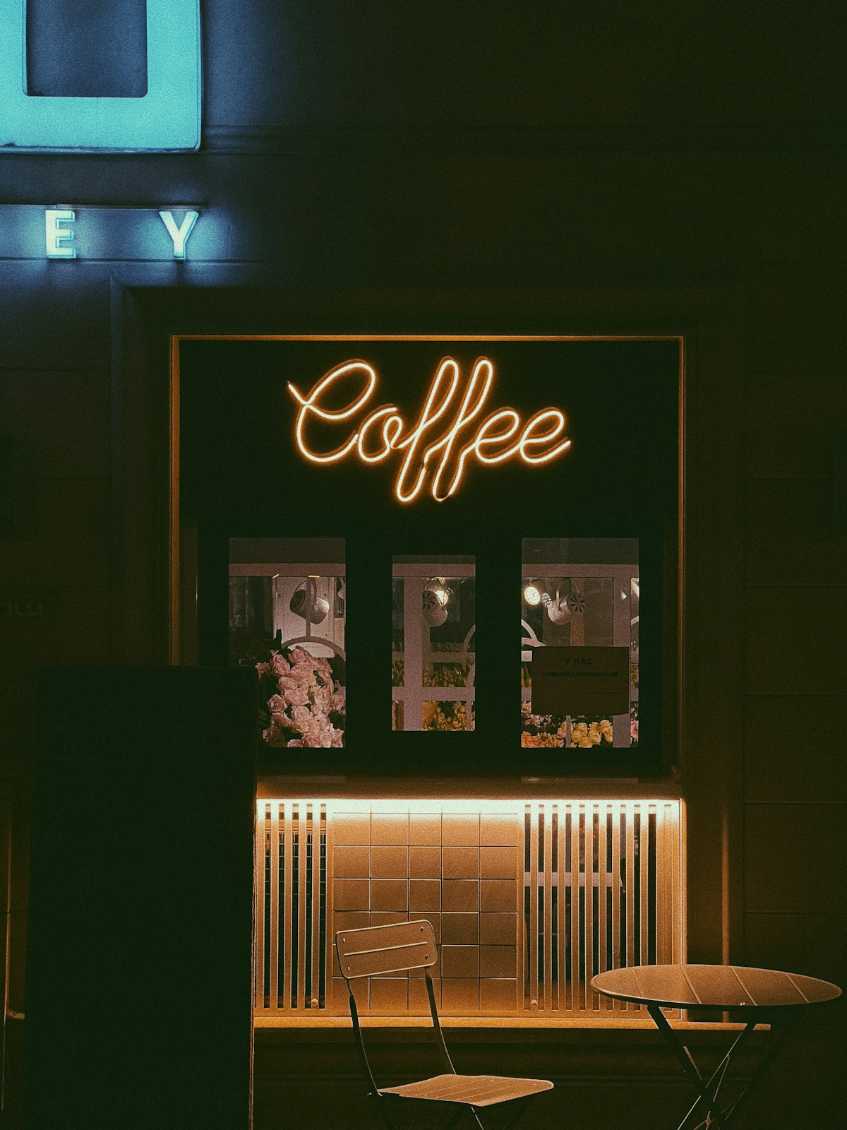 a coffee shop with a neon sign above it
