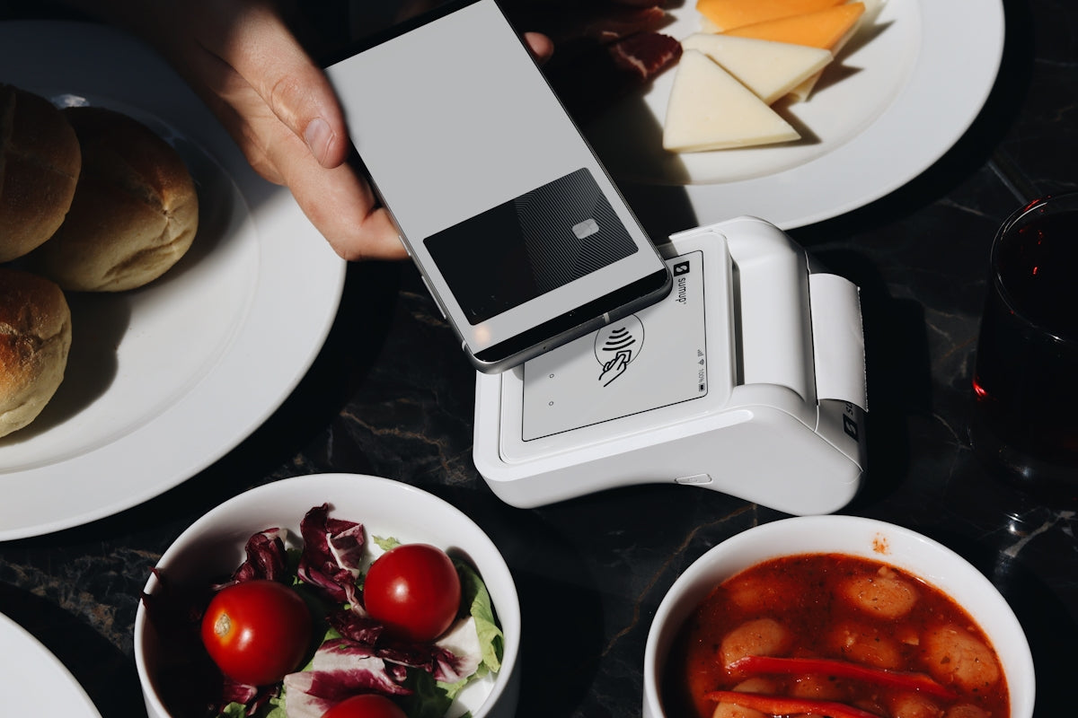A person holding a cell phone over a table full of food