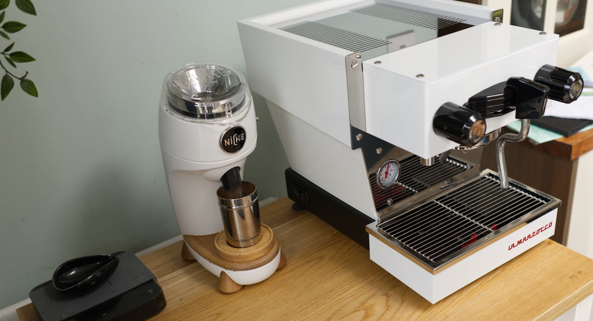 A white espresso machine and grinder are on display.