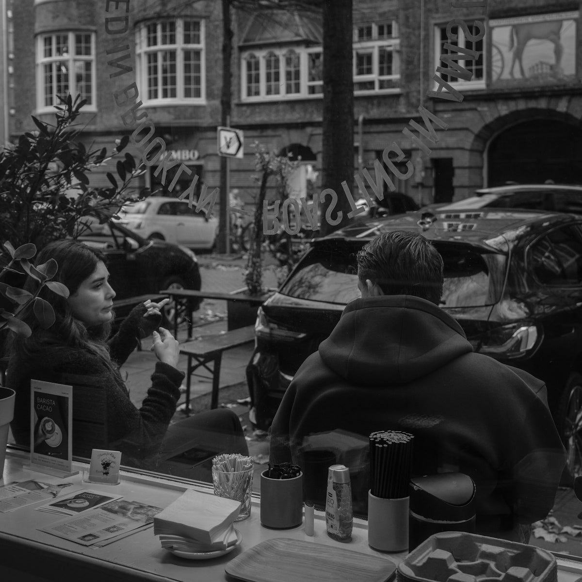 Two people sitting at a cafe, looking outside