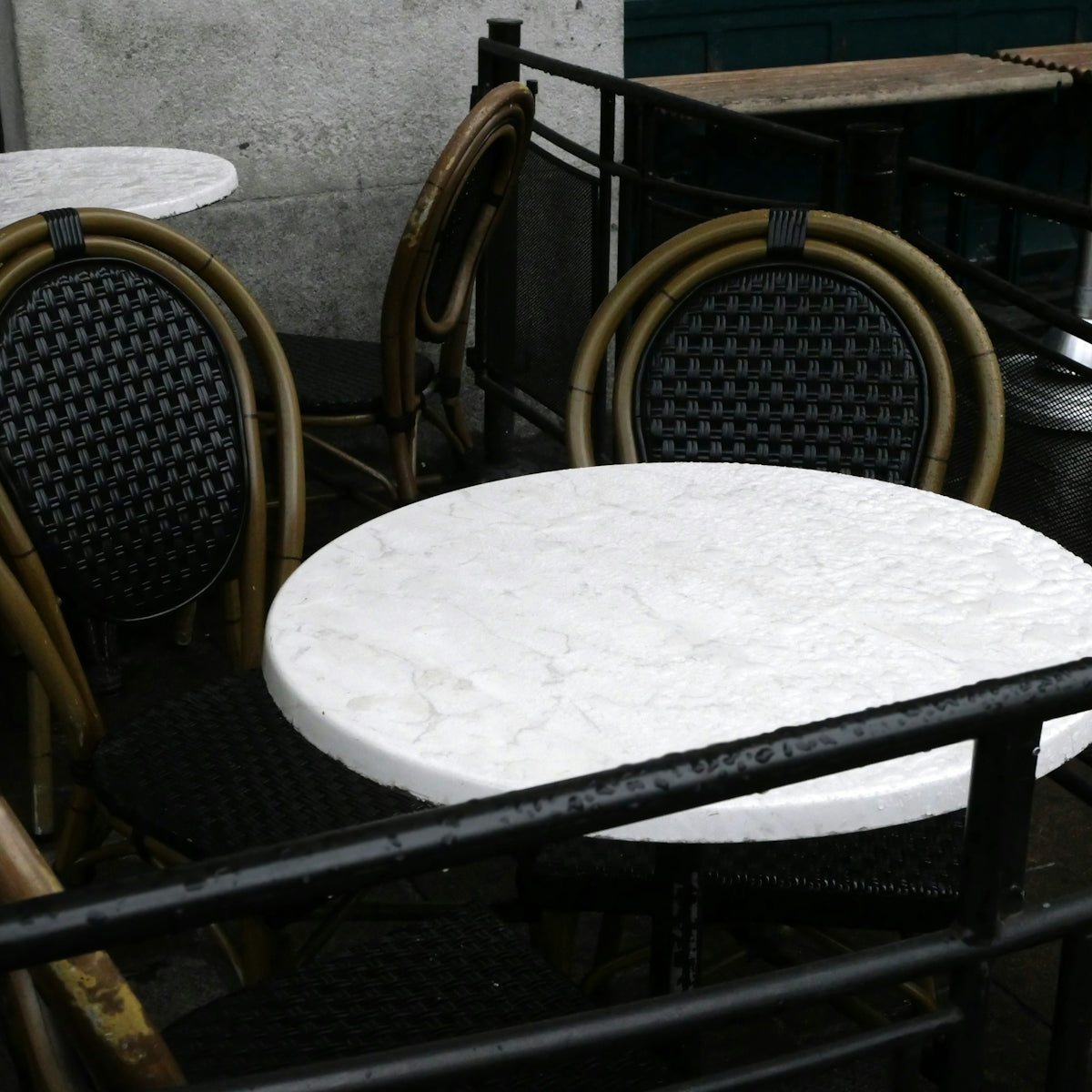 Empty outdoor cafe tables and chairs on a rainy day
